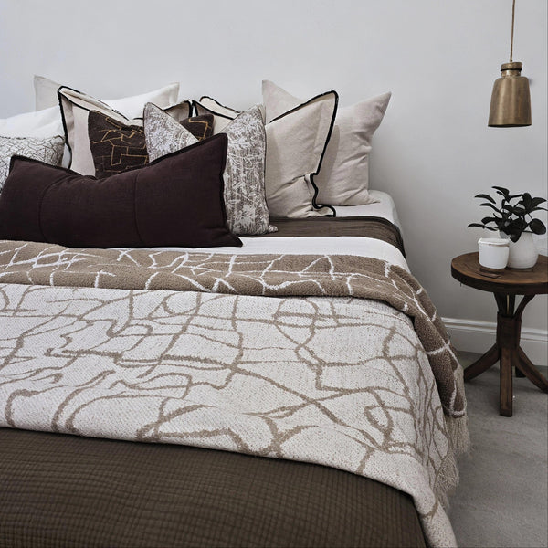 Bed with patterned bedding and pillows in a bedroom setting