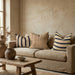 Beige sofa with striped and textured cushions in a room with a wooden coffee table and decorative items.