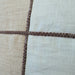 Close-up of fabric with brown stitching on a beige and white checkered pattern