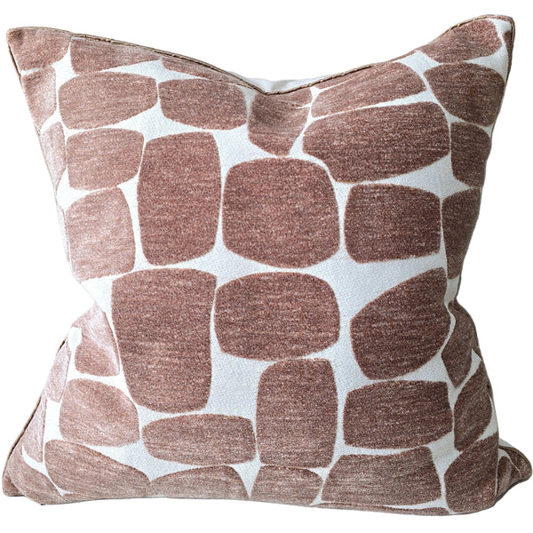 Burgandy Patterned pillow leaning against a light-colored wall with a colorful abstract painting in the background.