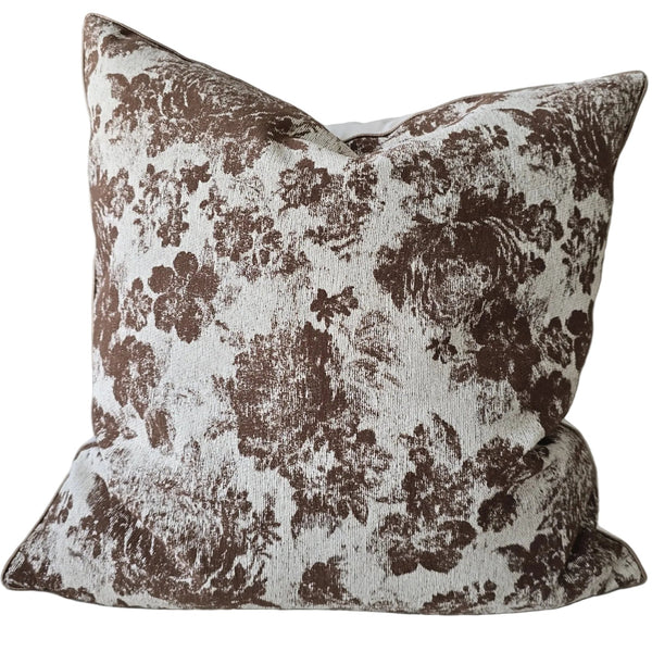 Floral patterned pillow on a light gray sofa with a wooden table in the background