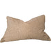 A rectangular beige textured throw pillow resting on a light beige upholstered sofa, with a wooden shelf and decorative objects partially visible on the left.
