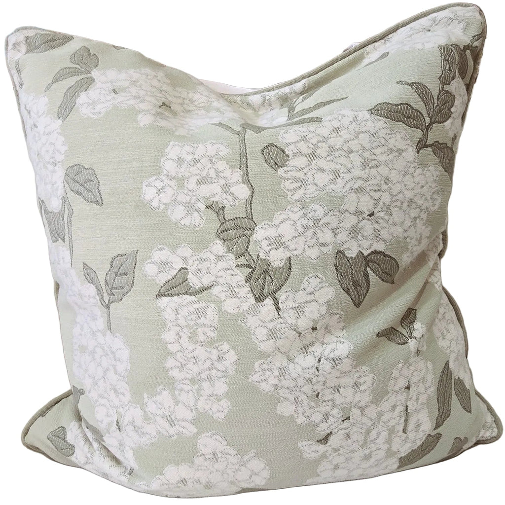 Floral-patterned pillow on a beige sofa with decorative vases in the background