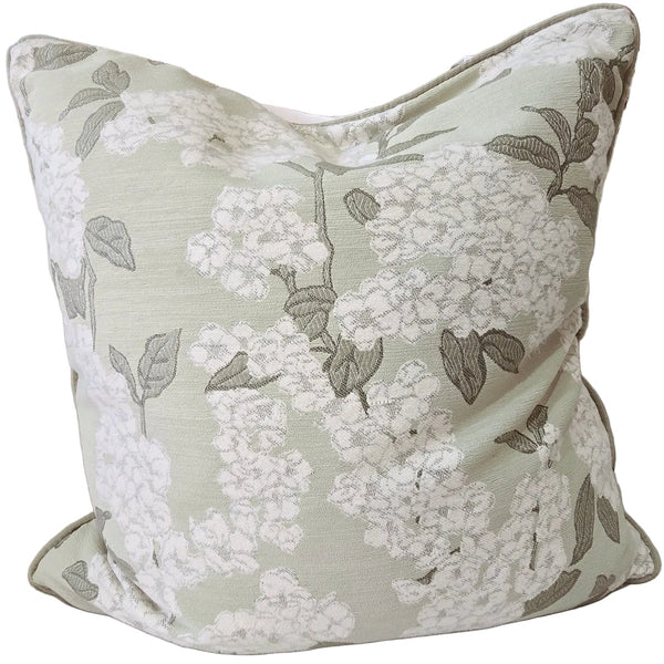 Floral-patterned pillow on a beige sofa with decorative vases in the background