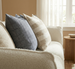 Decorative pillows on a sofa with a neutral color palette in a living room setting.